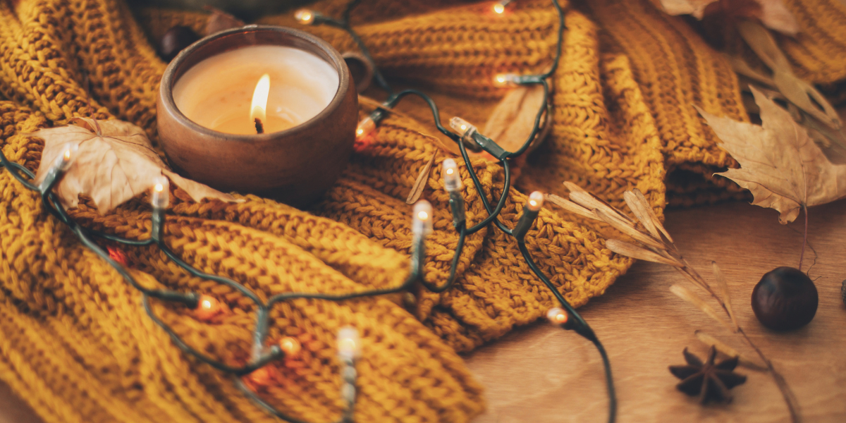 Fall colored string lights and a candle over a fall colored table mat with fall decorations.