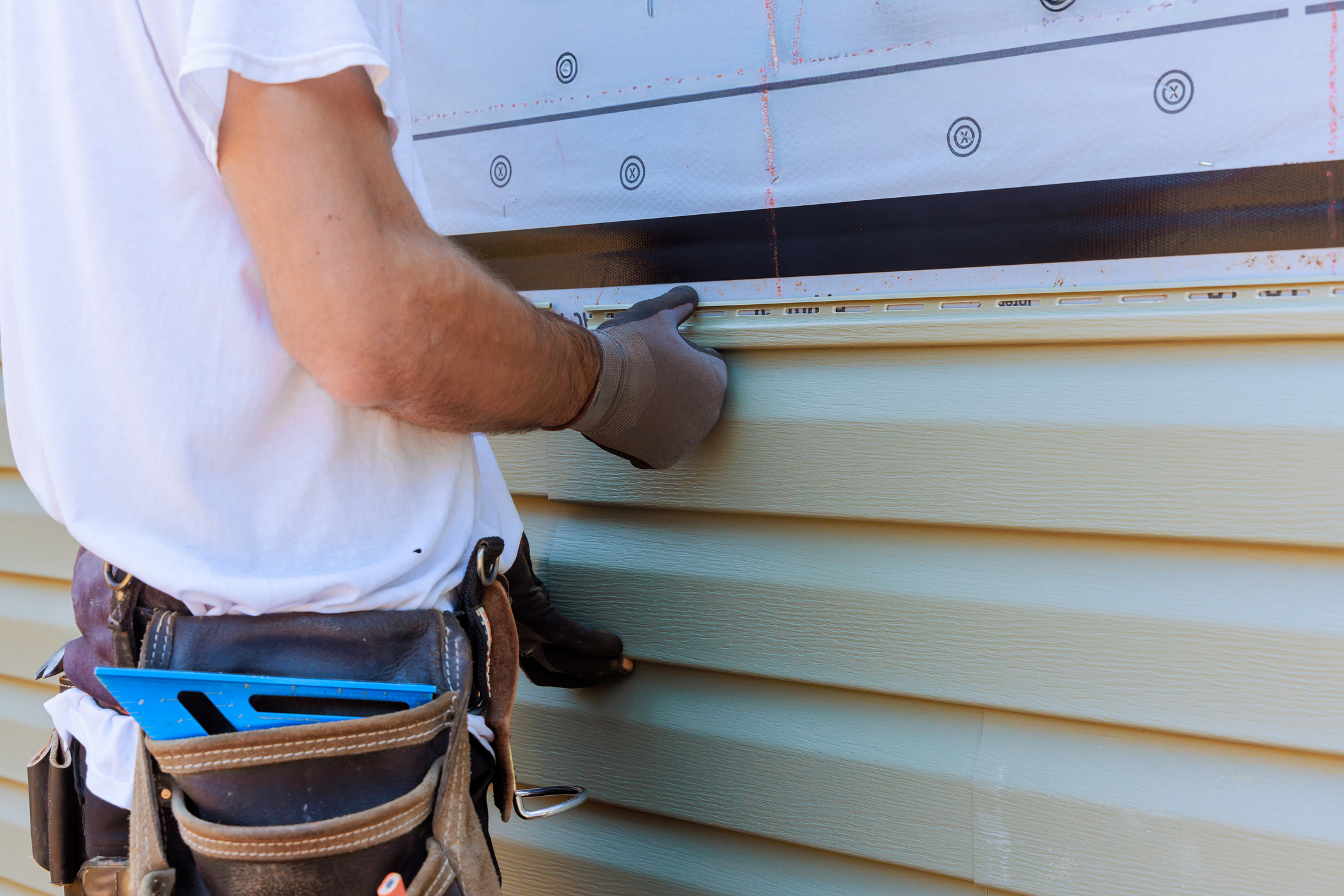 Handyman process installing vinyl PVC siding during construction on a house