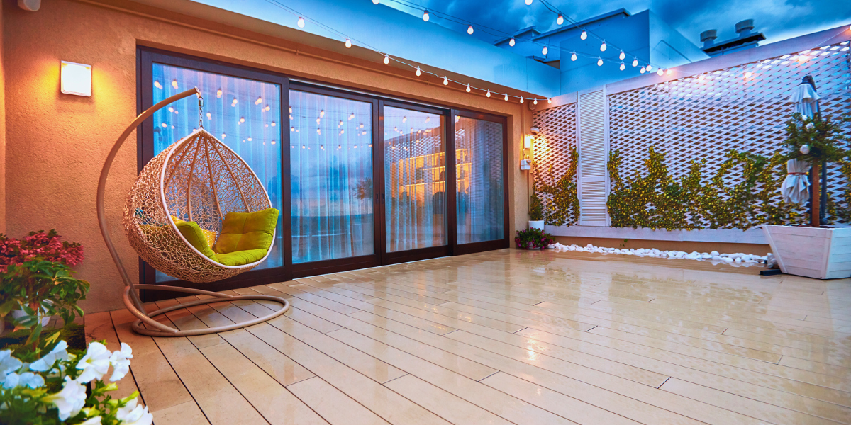 Patio with twinkle lights strung, a hanging chair, and sliding patio doors. 