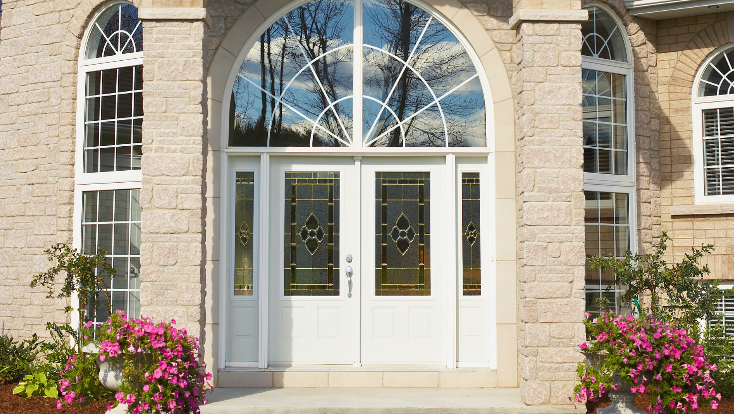 Large entryway with wood and glass doors and a glass arch over the doors.
