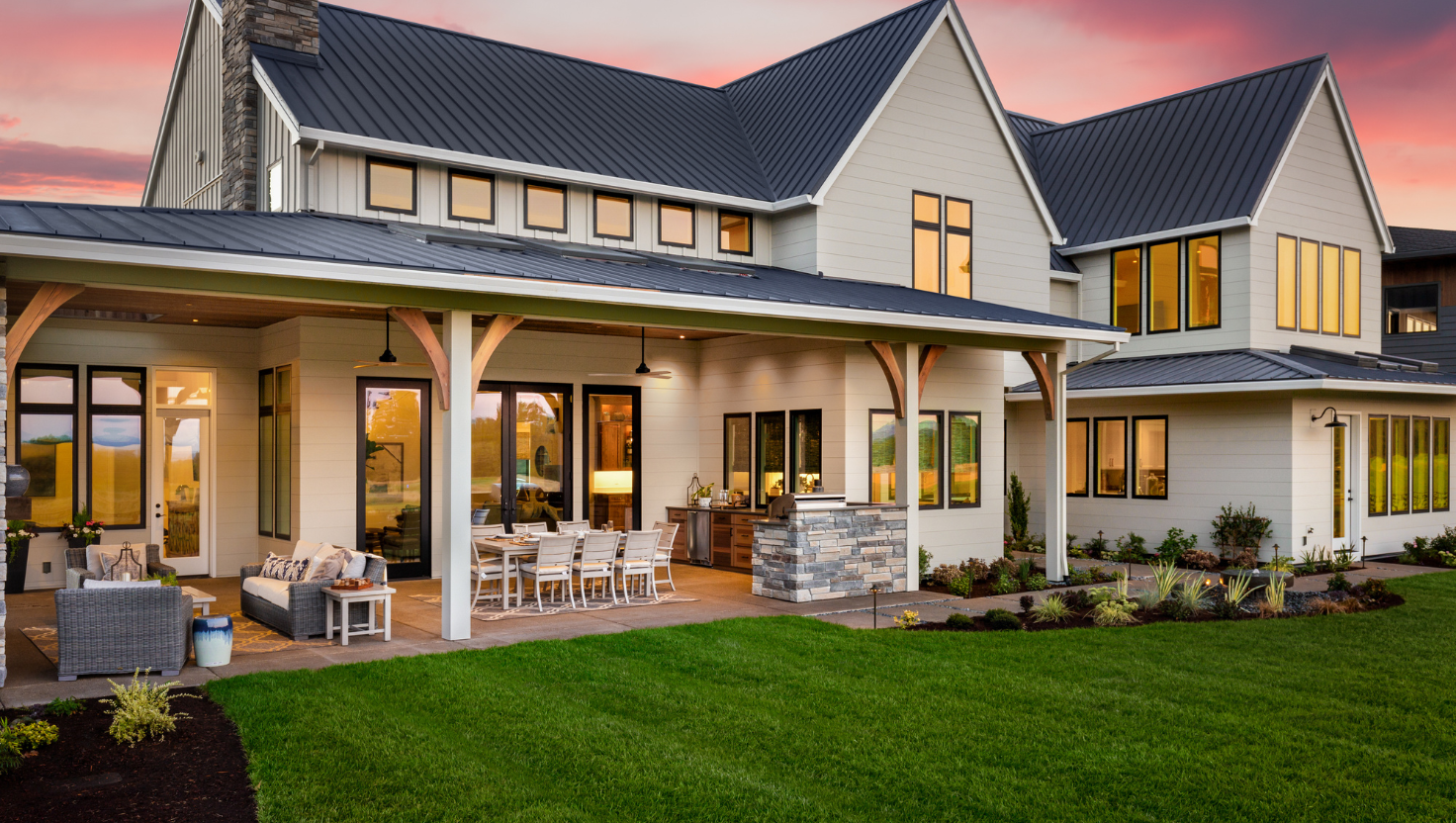 Outside of a modern house at night with outdoor lighting on the backyard patio.
