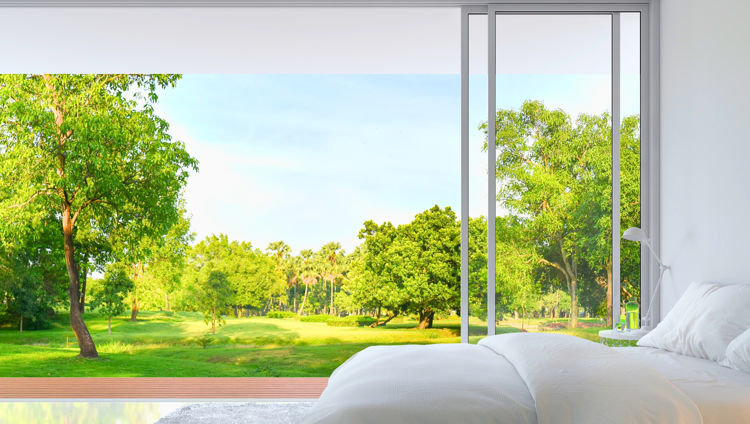 Bedroom view of sliding glass patio doors to a very lush and green outdoor view. 