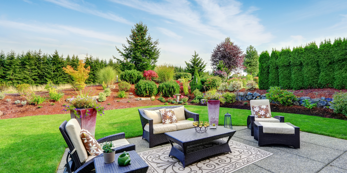 Backyard patio with modern furniture, colorful flowers and flower pots and sculptures. 