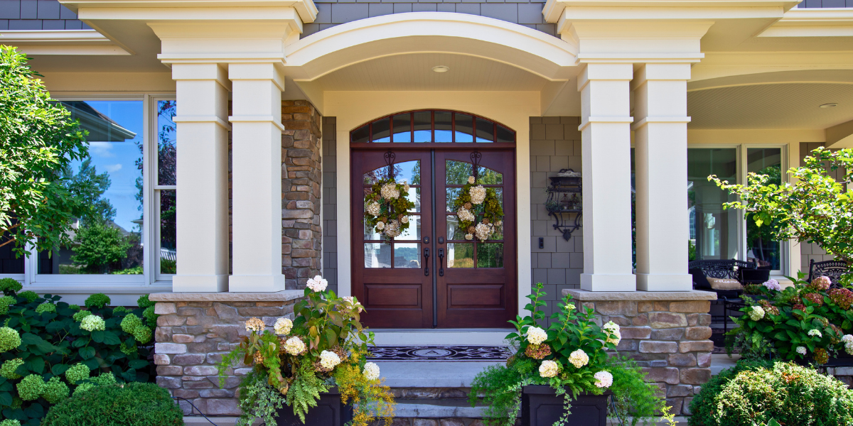 Entryway and porch with new doors and flower pots.