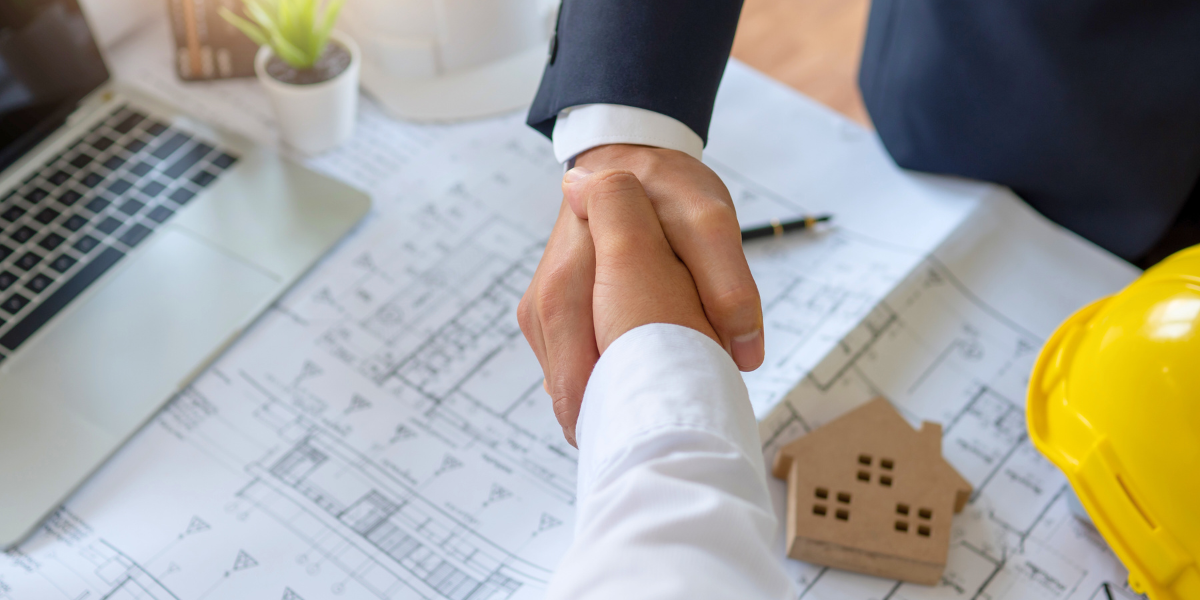 Construction papers under a business handshake.