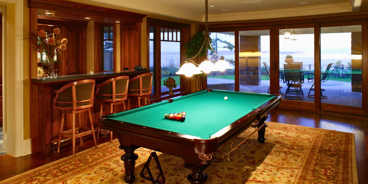 Basement that has been renovated with patio doors, a pool table, and bar.
