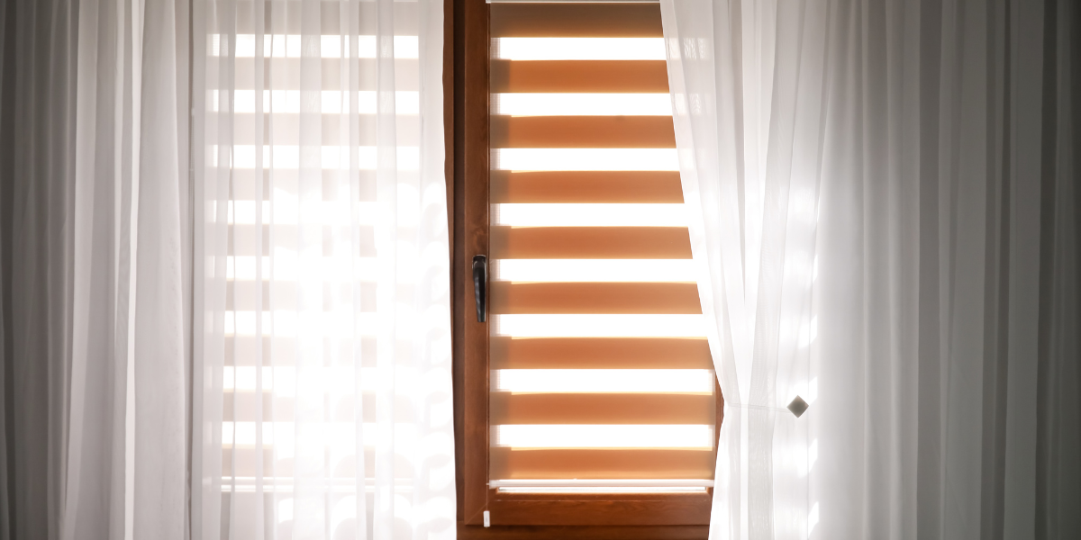 Sheer curtains with wood blinds on a window.
