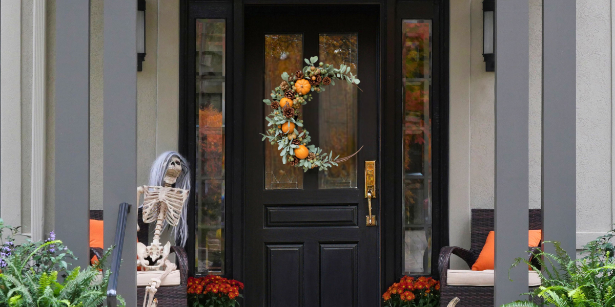 Crescent-shaped wreath hanging on a door surrounded by a fall decorated porch. 